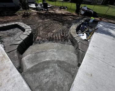 Curved stairs going from patio to lower backyard area with elevated flower beds